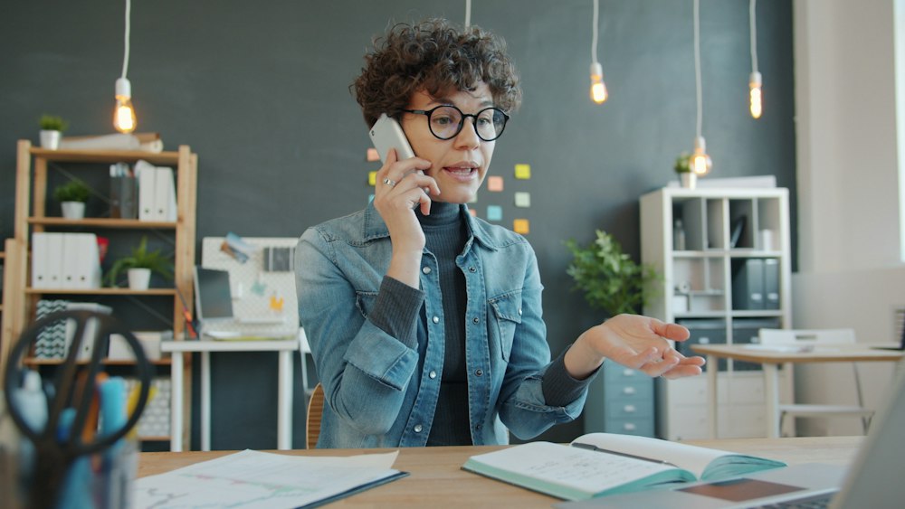Business owner taking a phone call at her office desk